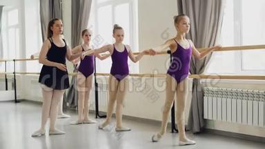 可爱的小女孩穿着明亮的紧身衣正在和艺术老师一起上古典芭蕾课学习腿部动作